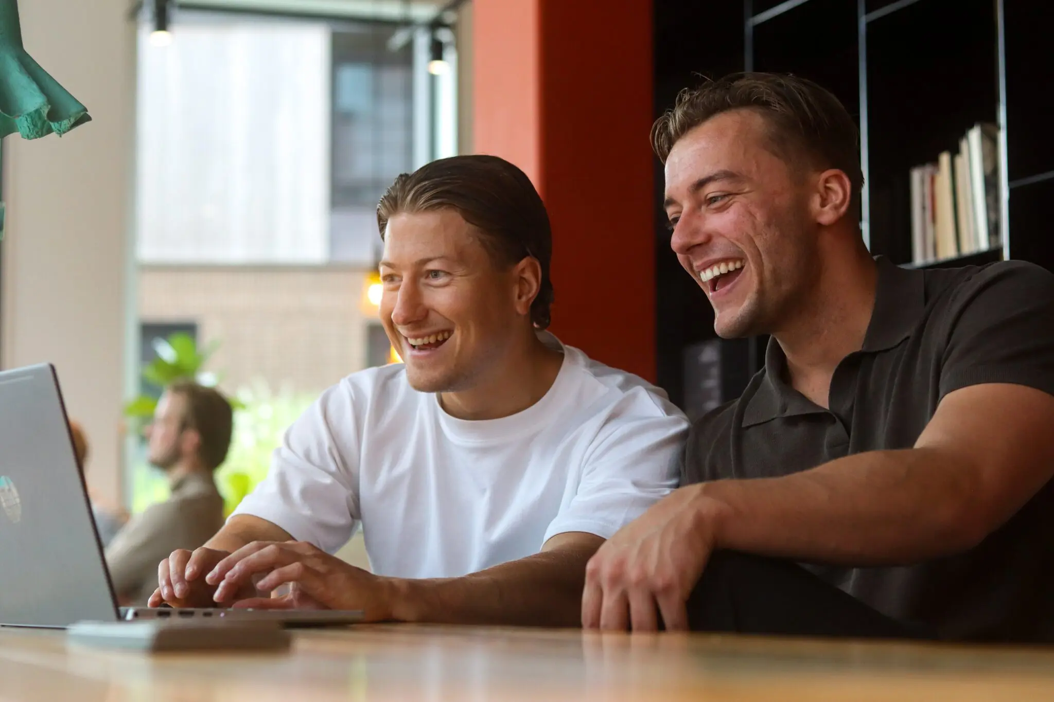 Twee collega’s van ConnectYou lachend achter een laptop